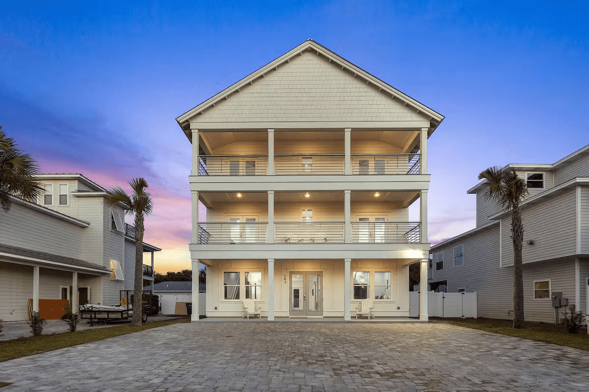 103 Shirah, a three-story Destin beach home lit at dusk above a paver driveway