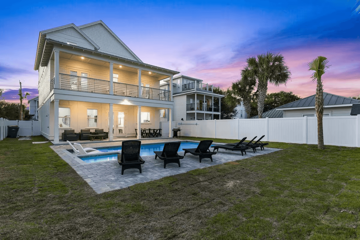 The private pool and loungers behind 103 Shirah glowing under a pink and purple Destin sunset