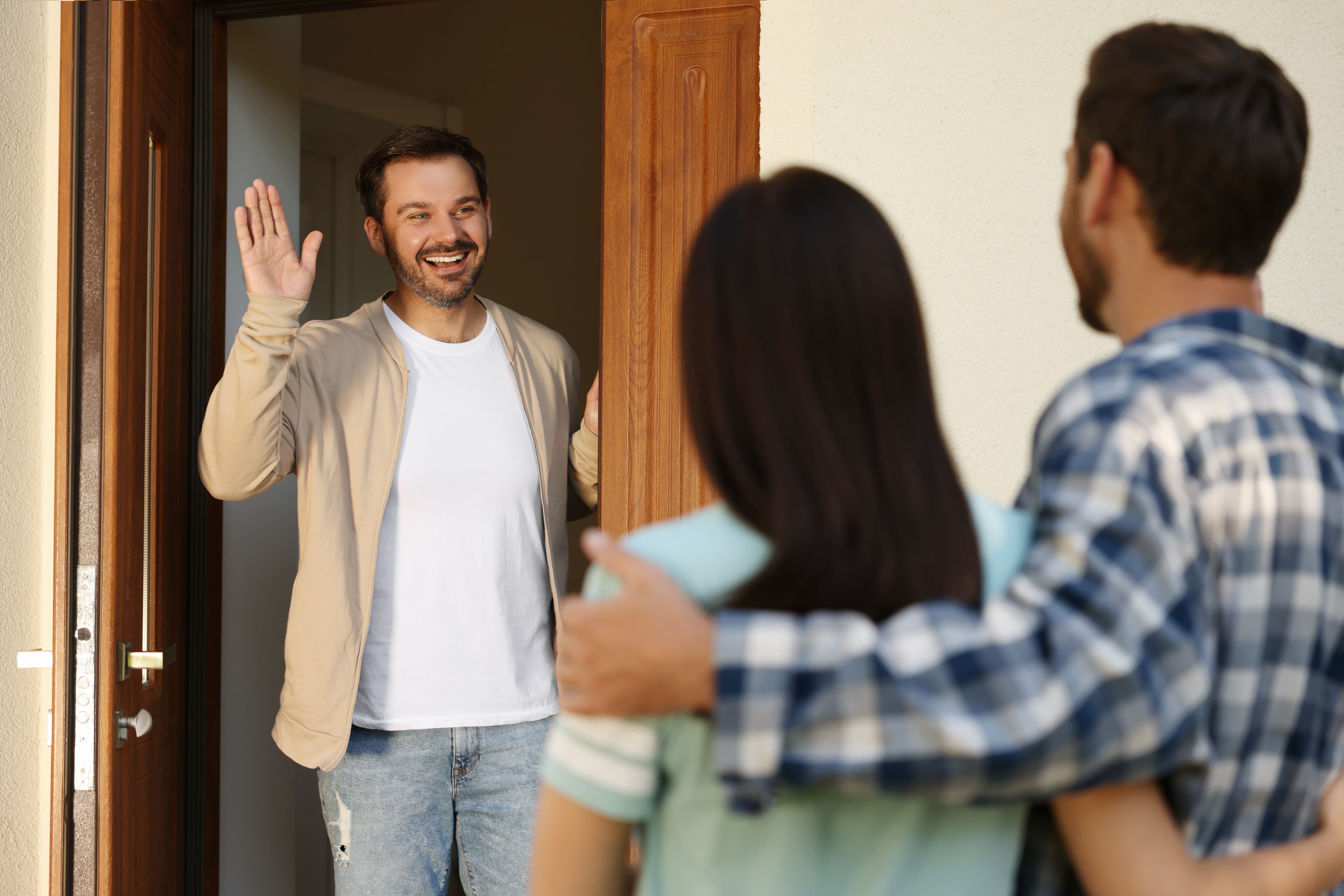 A homeowner waving hello as a couple arrives at the front door
